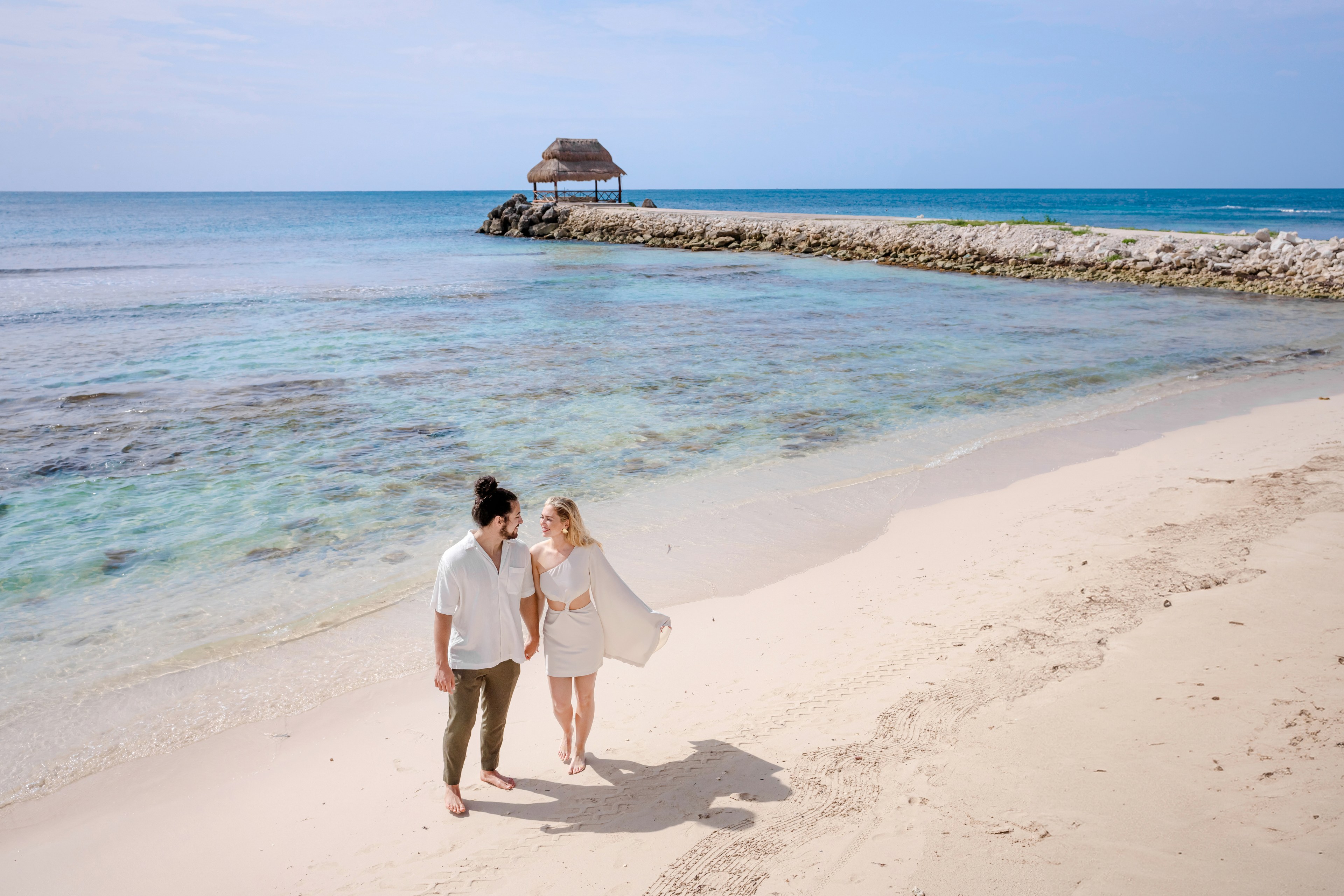 Couple embracing on a Cancun beach at golden hour, photographed editorially by IVAE Studios.