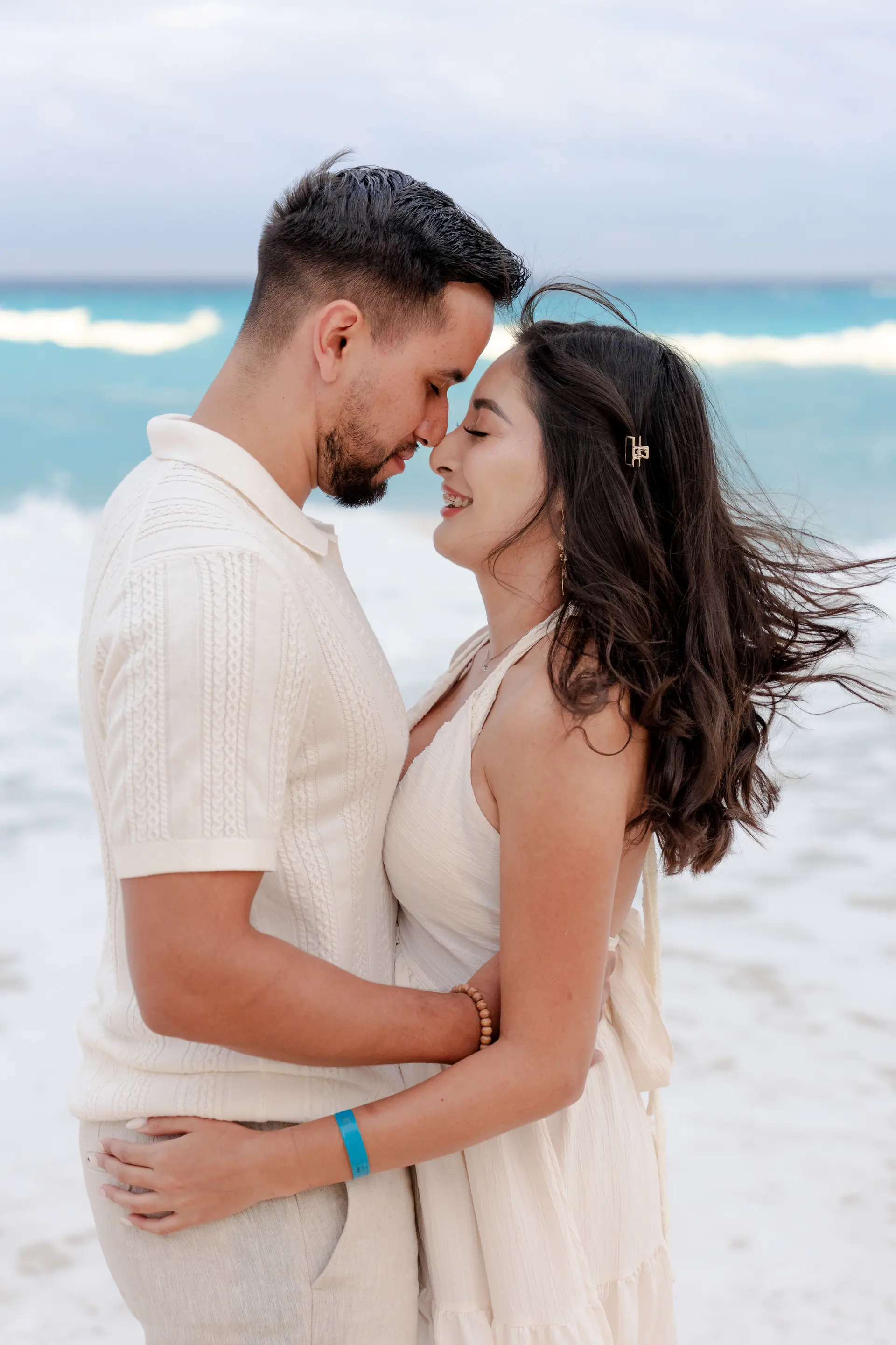 Couple embracing on a Riviera Maya beach as natural light beams reflect off the Caribbean water