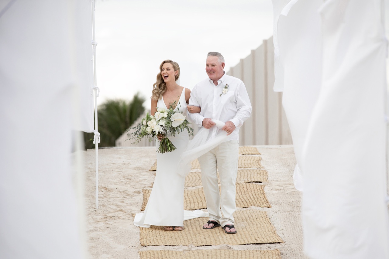 A bride walking down a beach aisle with her father at a destination wedding photographed by IVAE Studios